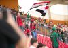 Soccer fans in the stadium wave Egyptian flags, showing their support during a lively sports match.