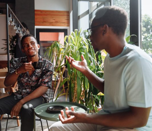 Two friends having a lively conversation over coffee in a cozy coffee shop setting.
