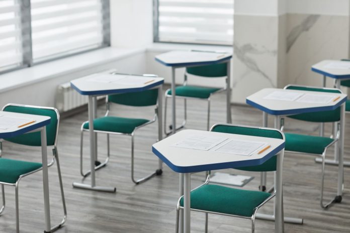 how-to-get-your-ged-in-bayonne-nj An empty classroom with arranged desks, exam papers, and pencils ready for students.