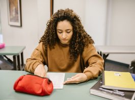 Young woman studying for an exam in a college classroom with books and notes.