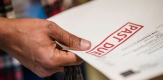A close-up of a hand holding a document with a 'Past Due' stamp, highlighting financial urgency.