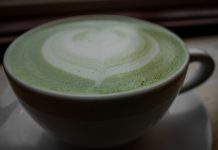 Close-up of a frothy matcha latte with heart latte art in a ceramic cup, warm and inviting.