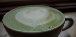 Close-up of a frothy matcha latte with heart latte art in a ceramic cup, warm and inviting.