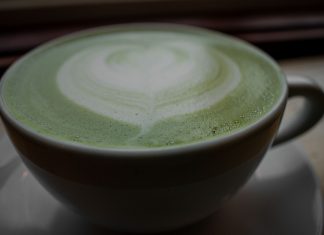 Close-up of a frothy matcha latte with heart latte art in a ceramic cup, warm and inviting.