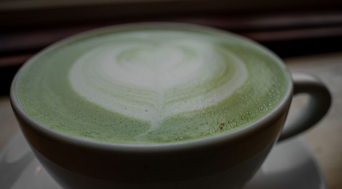 Close-up of a frothy matcha latte with heart latte art in a ceramic cup, warm and inviting.