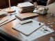 Jersey City Budget Gap Narrows, But Tax Hike Question Lingers Close-up of an office desk with tax documents, coins, glasses, and an old phone, symbolizing finance and organization.