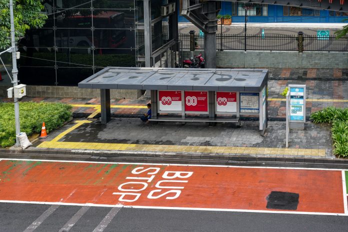 Bus stop in Jakarta, Indonesia with empty seating area and modern urban surroundings.