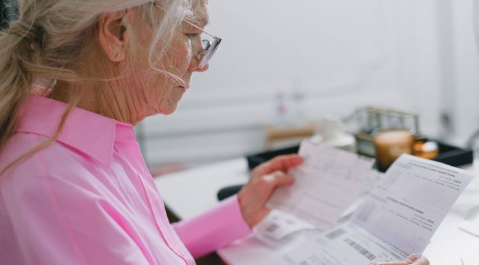 Jersey City launches ‘Senior Freeze’ campaign to help seniors claim tax relief Elderly woman in a pink shirt reviewing paperwork at home.