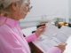 Jersey City launches ‘Senior Freeze’ campaign to help seniors claim tax relief Elderly woman in a pink shirt reviewing paperwork at home.