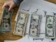 Person holds US dollars over financial papers, showing income or budget analysis.