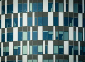Jersey City Real Estate Firm Expands as Homes Stay Pricey Close-up of a modern office building facade with geometric patterns and glass windows.
