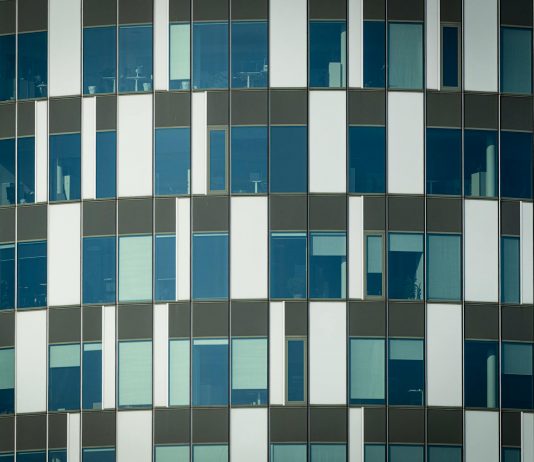 Close-up of a modern office building facade with geometric patterns and glass windows.