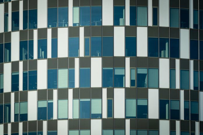 Close-up of a modern office building facade with geometric patterns and glass windows.
