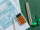 Jersey City’s Budget Squeeze: Taxes Up or Services Cut? Flat lay of tax forms, calculator, pencils, and clips on green surface, ideal for finance or accounting themes.