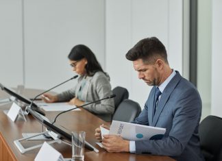 Jersey City School Board Approves Promotions, Downtown Rezoning Study Business professionals in a conference setting, focusing on documents and reports.