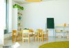 A well-lit, colorful kindergarten classroom with chairs, tables, and educational materials.