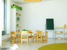 A well-lit, colorful kindergarten classroom with chairs, tables, and educational materials.