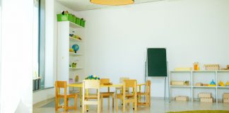 A well-lit, colorful kindergarten classroom with chairs, tables, and educational materials.