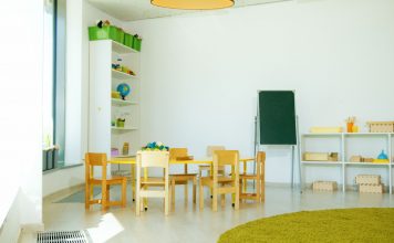A well-lit, colorful kindergarten classroom with chairs, tables, and educational materials.