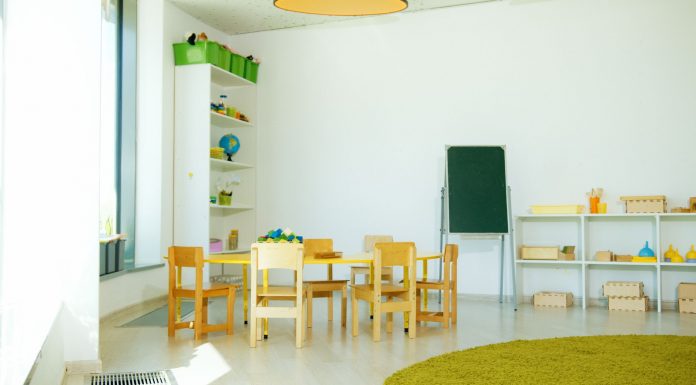 A well-lit, colorful kindergarten classroom with chairs, tables, and educational materials.