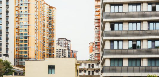 Journal Square Tower Plan Brings 150 Public Parking Spots, Affordable Units High-rise apartment buildings with parked cars in front captured in Sichuan, China.