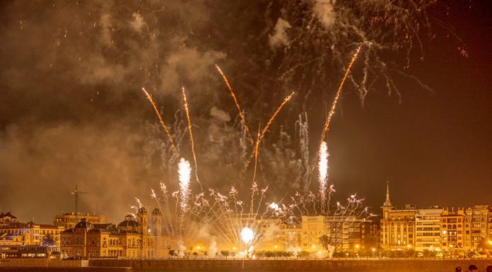 Vibrant fireworks light up the night sky over a bustling waterfront city, captivating an excited crowd below.