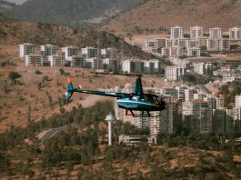 Aerial view of a helicopter flying over a town surrounded by hills and trees