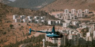 Aerial view of a helicopter flying over a town surrounded by hills and trees