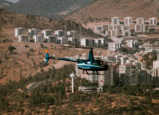 ÚLTIMA HORA: Condado avanza en lucha legal contra helipuerto ruidoso Aerial view of a helicopter flying over a town surrounded by hills and trees
