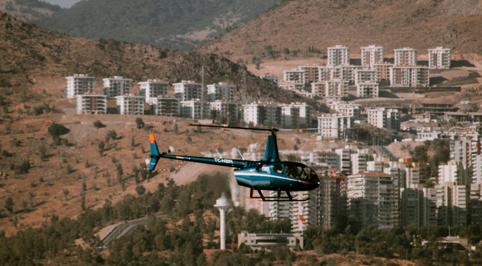 ÚLTIMA HORA: Condado avanza en lucha legal contra helipuerto ruidoso Aerial view of a helicopter flying over a town surrounded by hills and trees