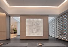 Spacious modern yoga studio interior featuring a striking wall art piece and yoga mats on wooden flooring.