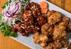 Close-up of a Korean fried chicken platter with garnishes, perfect for food enthusiasts.