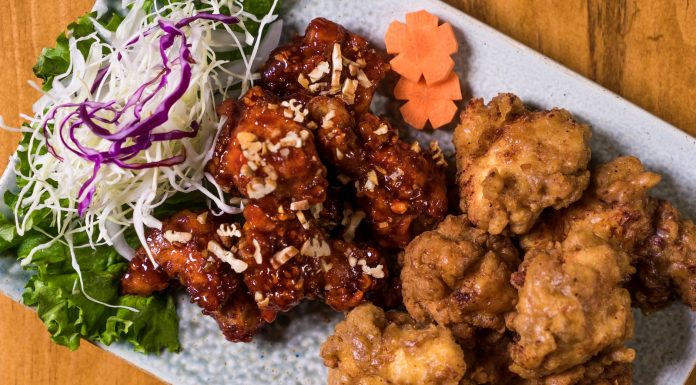 Close-up of a Korean fried chicken platter with garnishes, perfect for food enthusiasts.