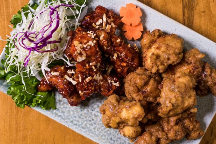 ltima-hora-don-chicken-abrir-local-en-jersey-city Close-up of a Korean fried chicken platter with garnishes, perfect for food enthusiasts.