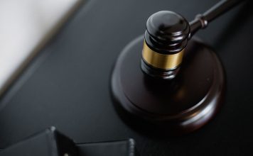 From above of wooden gavel on round surface near folders on table in courtroom