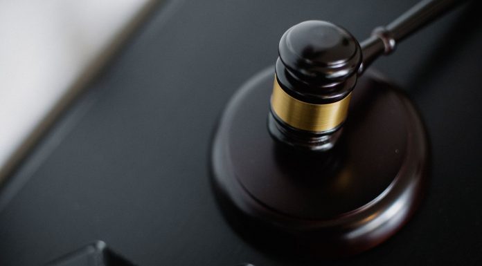 From above of wooden gavel on round surface near folders on table in courtroom