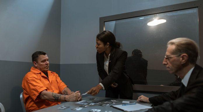 A tense interrogation scene with lawyers questioning an inmate in a prison setting.