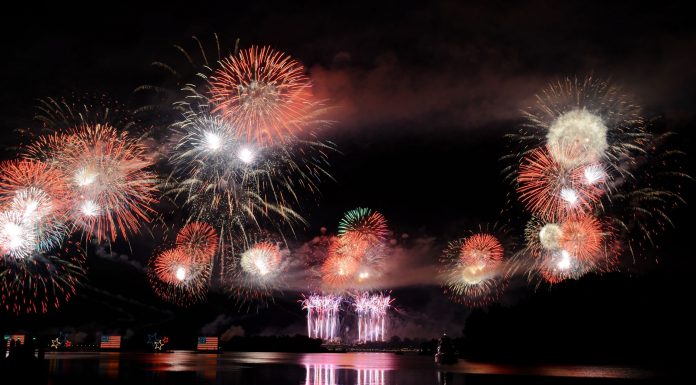 ÚLTIMA HORA: Fiesta del 4 de Julio regresa a Hoboken en 2026 Vibrant fireworks illuminate the night sky, reflecting brilliantly over the calm lake surface.
