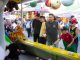 A diverse group of people engages in a fun carnival game, surrounded by vibrant festival activities.