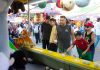 A diverse group of people engages in a fun carnival game, surrounded by vibrant festival activities.