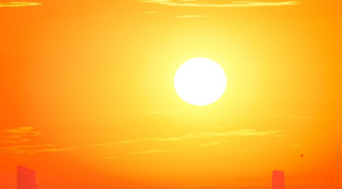 A city skyline silhouetted against a vivid, orange sunset sky.