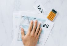 Close-up of a hand on tax form 1040 with a calculator on a desk.