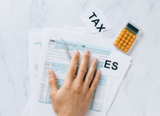 Close-up of a hand on tax form 1040 with a calculator on a desk.