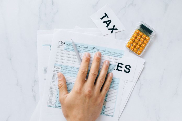 ltima-hora-jersey-city-impulsa-ayuda-fiscal-para- Close-up of a hand on tax form 1040 with a calculator on a desk.