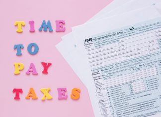 ÚLTIMA HORA: Jersey City lanza campaña para alivio fiscal a mayores 1040 tax forms with colorful 'Time to Pay Taxes' letters.