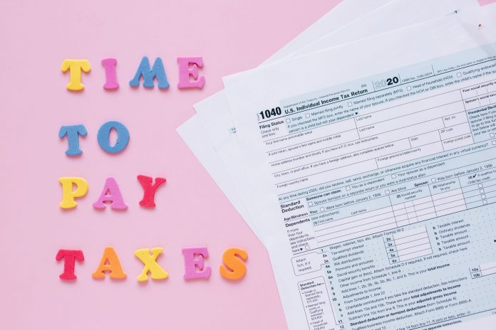 ltima-hora-jersey-city-lanza-campa-a-para-alivio- 1040 tax forms with colorful 'Time to Pay Taxes' letters.