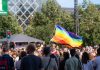 ÚLTIMA HORA: Jersey City Pride inicia su temporada de verano Vibrant pride parade scene with a waving rainbow flag amidst a diverse crowd outdoors.