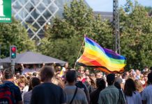 ÚLTIMA HORA: Jersey City Pride inicia su temporada de verano Vibrant pride parade scene with a waving rainbow flag amidst a diverse crowd outdoors.