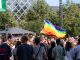 Vibrant pride parade scene with a waving rainbow flag amidst a diverse crowd outdoors.