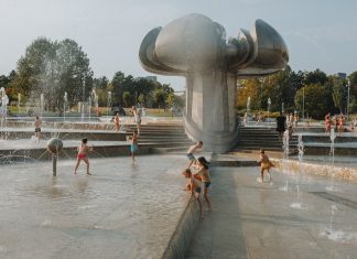 Happy children enjoy a sunny day playing in an urban fountain park with modern sculptures.